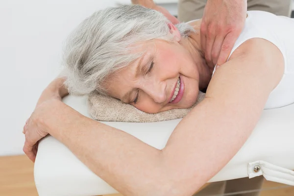 Fisioterapeuta massajando o ombro de uma mulher idosa — Fotografia de Stock