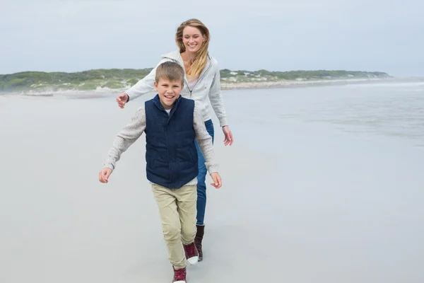 Lachende vrouw en jongen draait op strand — Stockfoto