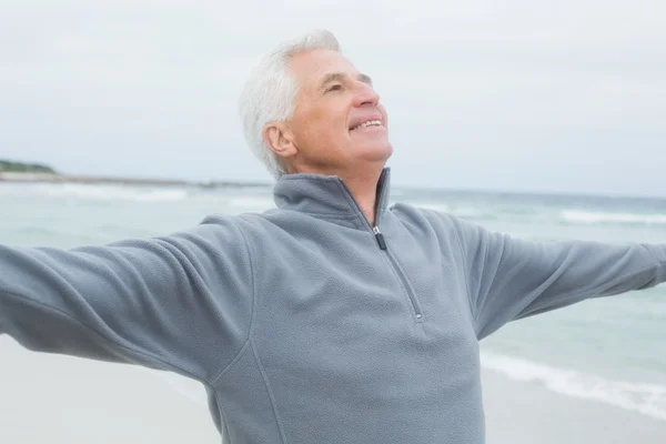 Uomo anziano con le braccia tese in spiaggia — Foto Stock