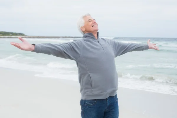 Uomo anziano con le braccia tese in spiaggia — Foto Stock