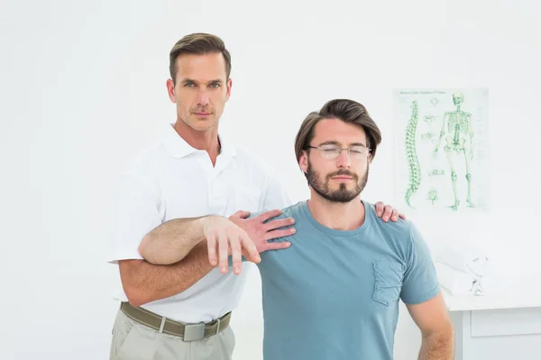 若い男の腕を伸ばして男性理学療法士 — ストック写真