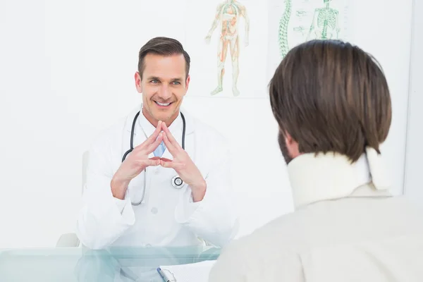 Дружелюбный врач слушает пациента с концентрацией внимания за столом — стоковое фото