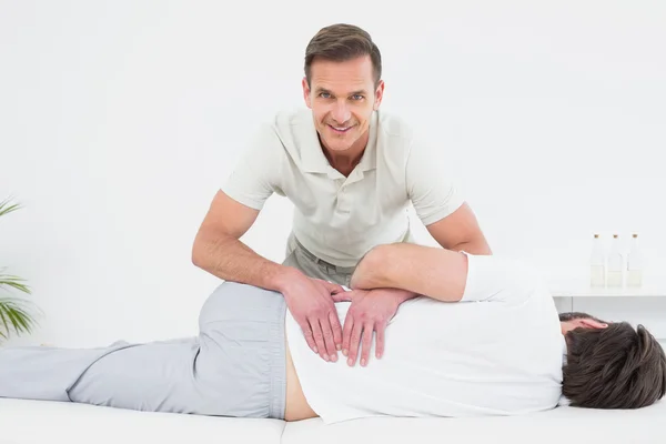 Fisioterapeuta sorridente examinando as costas do homem — Fotografia de Stock