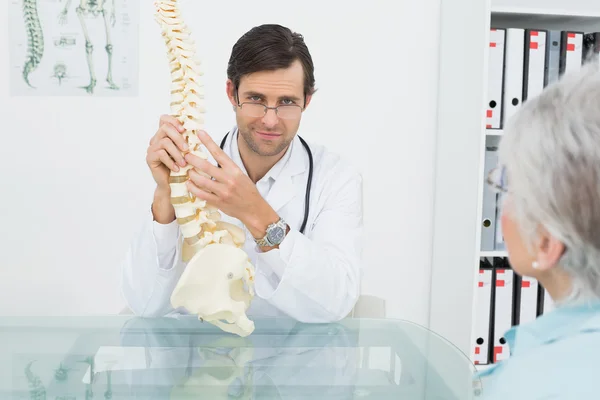 Médico masculino explicando a coluna vertebral a um paciente sênior — Fotografia de Stock