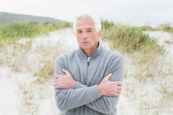 Casual senior man feeling cold at beach — Stock Photo, Image