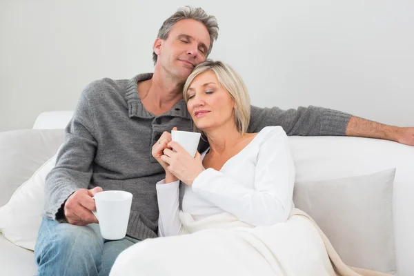 Avslappnad par med kaffekoppar i vardagsrum — Stockfoto