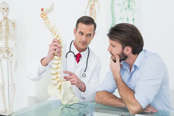 Homme médecin expliquant la colonne vertébrale à un patient — Photo