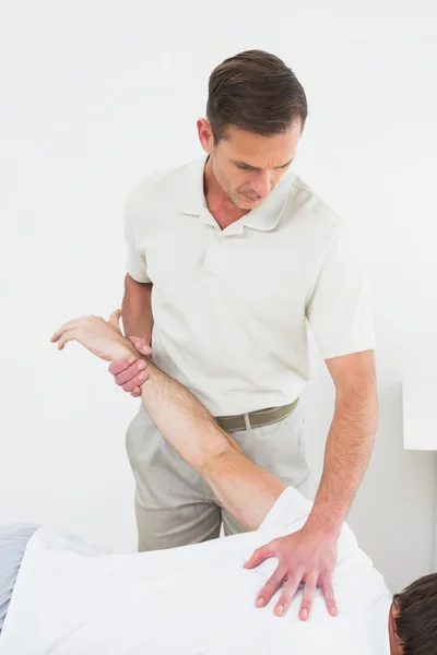 Fisioterapeuta masculino esticando a mão de um homem — Fotografia de Stock