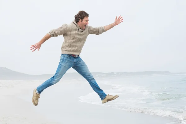 Vue latérale d'un homme décontracté sautant à la plage — Photo