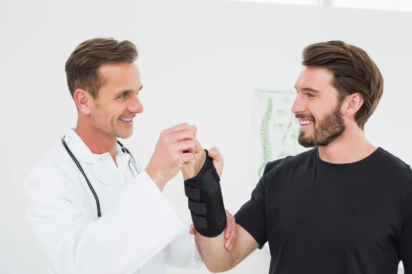 Fisioterapeuta masculino examinando la muñeca de un joven — Foto de Stock