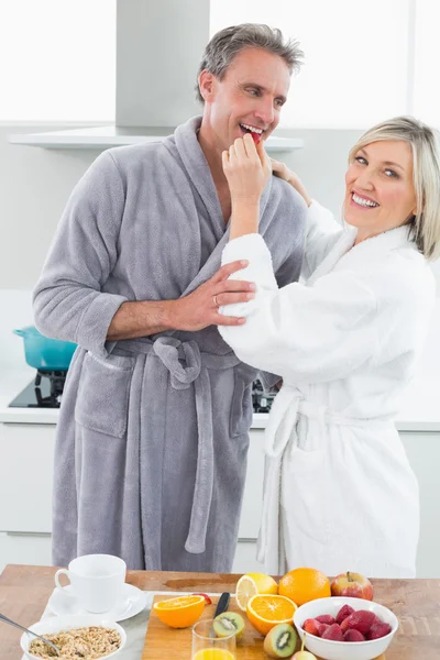 Woman feeding man in the kitchen — Stock Photo, Image