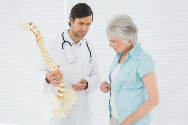 Doutor explicando a coluna vertebral para um paciente sênior — Fotografia de Stock