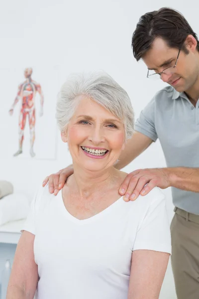 Fisioterapeuta masculino masajeando los hombros de una mujer mayor — Foto de Stock