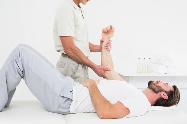 Fisioterapeuta masculino examinando a mão de um homem — Fotografia de Stock