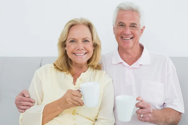 Ontspannen senior koppel met koffie cups thuis — Stockfoto