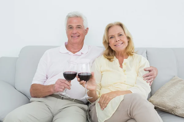 Senior couple toasting wine glasses at home