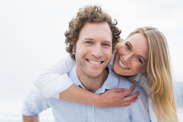 Man piggybacking woman at beach