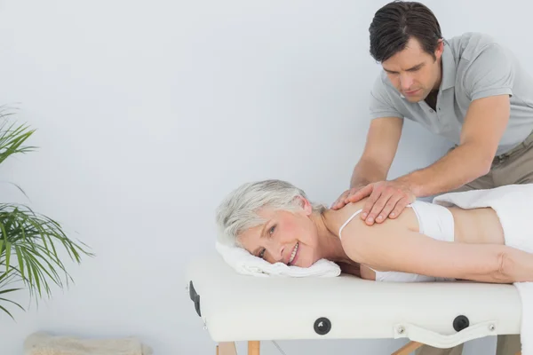 Fisioterapeuta masculino masajeando la espalda de una mujer mayor — Foto de Stock