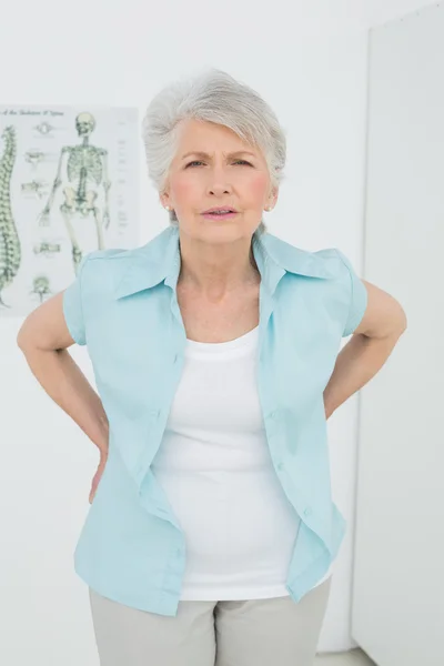 Senior woman with back pain in medical office — Stock Photo, Image
