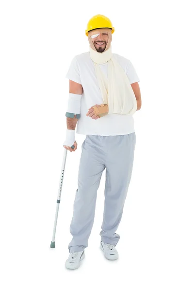 Young man in hard hat with broken hand and crutch — Stock Photo, Image