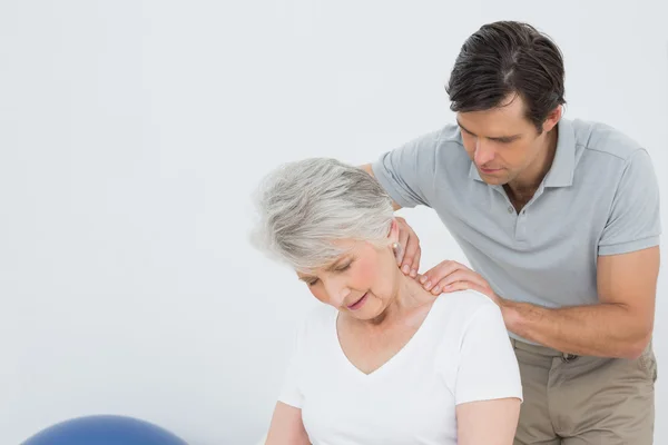 Fisioterapeuta masajeando el cuello de una mujer mayor — Foto de Stock