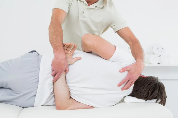 Fisioterapeuta masculino examinando la espalda del hombre — Foto de Stock