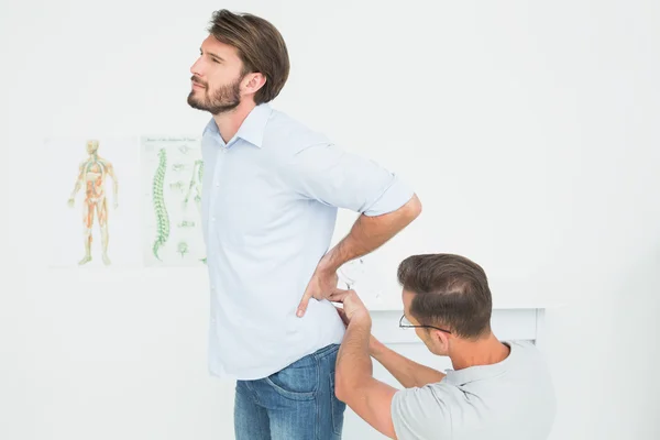 Fisioterapeuta masculino examinando la espalda del hombre — Foto de Stock