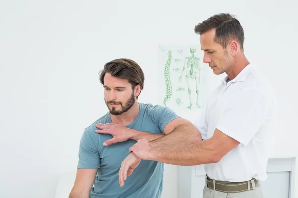 Fisioterapeuta masculino esticando a mão de um jovem — Fotografia de Stock