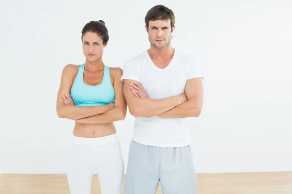 Passar unga par med armarna korsade i fitnesstudio — Stockfoto