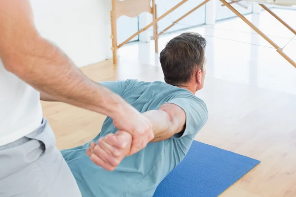 Terapeuta que ayuda al hombre con ejercicios de estiramiento — Foto de Stock
