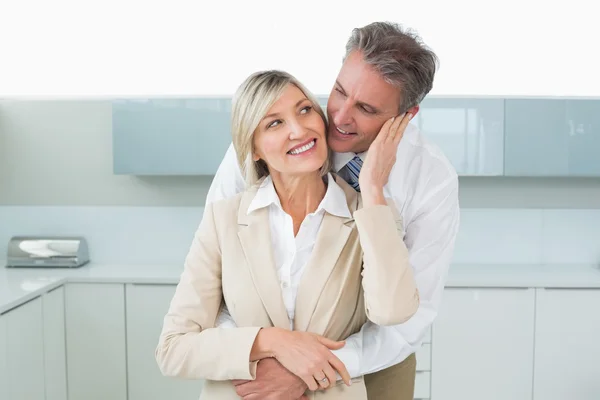 Man embracing happy woman from behind in kitchen — Stock Photo, Image