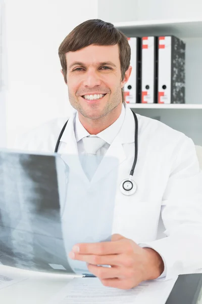 Médico sonriente con radiografía de columna vertebral en el consultorio médico —  Fotos de Stock