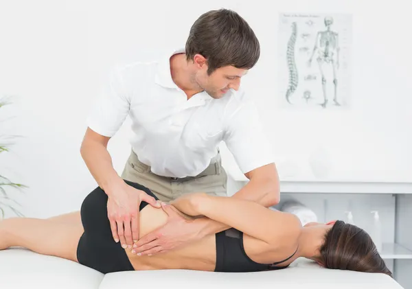 Fysiotherapeut masseren vrouw terug in medische kantoor — Stockfoto
