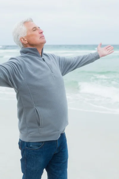 Senior man met armen gestrekt op strand — Stockfoto