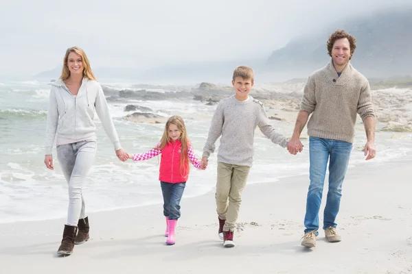 Gelukkige familie van vier lopen hand in hand op strand — Stockfoto