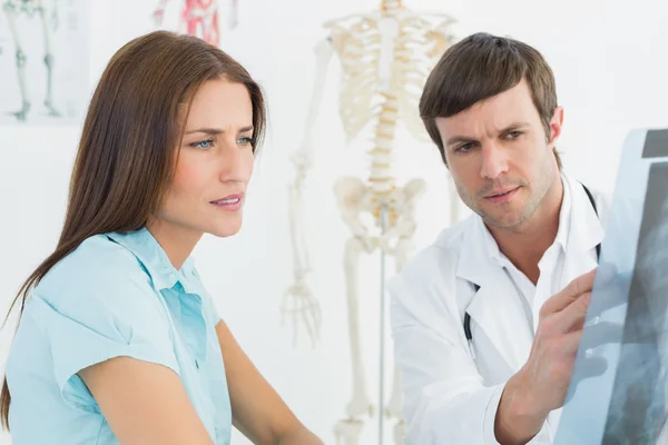 Médico do sexo masculino que explica a radiografia da coluna para paciente do sexo feminino — Fotografia de Stock