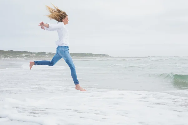 Sidovy av en casual kvinna hoppa på stranden — Stockfoto