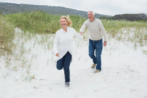 Веселая пожилая пара бегает по пляжу — стоковое фото