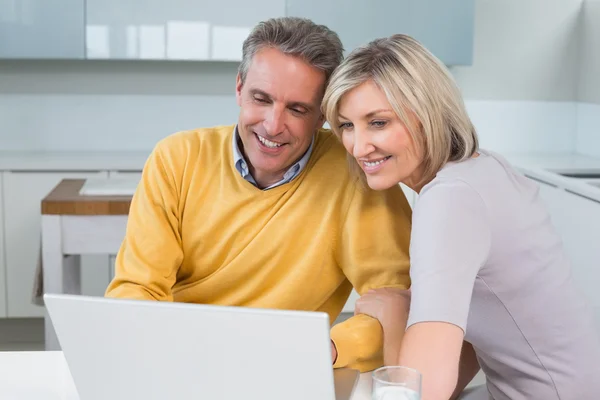 Happy couple using laptop in kitchen — Stock Photo, Image