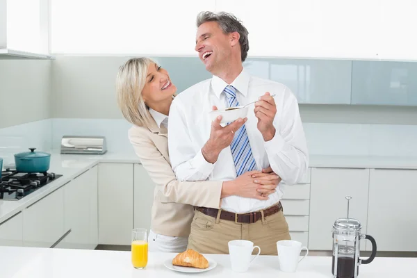 Woman embracing a happy man from behind in kitchen — Stock Photo, Image