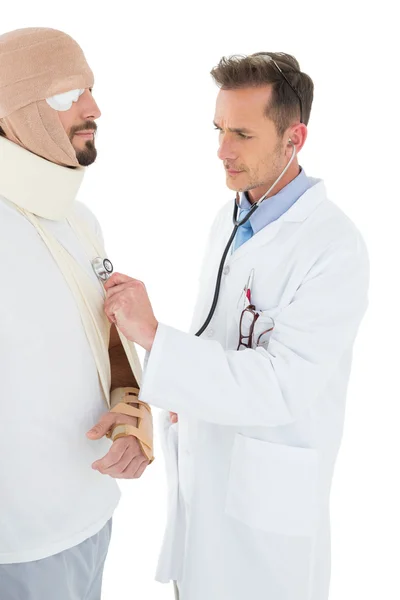 Médico auscultando paciente amarrado em curativo com estetoscópio — Fotografia de Stock