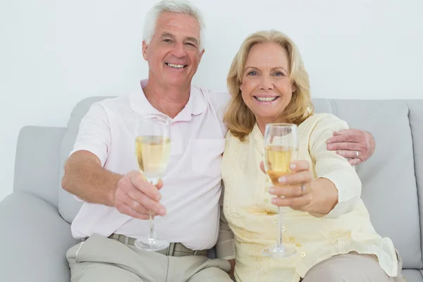 年长的夫妇在家里抱着香槟笛子 — 图库照片