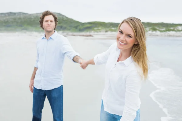 Lachende casual paar hand in hand op strand — Stockfoto