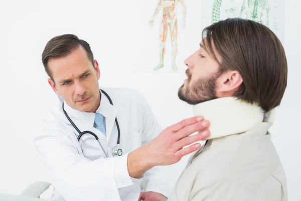 Médico masculino examinando el cuello de un paciente — Foto de Stock