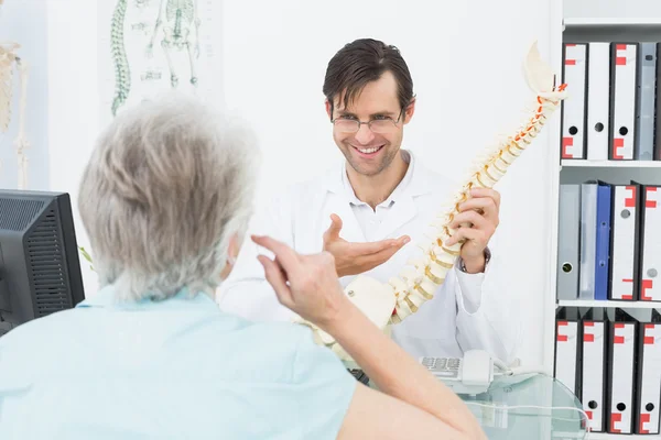 Médico amigável explicando coluna vertebral para um paciente sênior — Fotografia de Stock