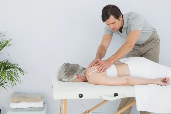 Fisioterapeuta do sexo masculino massageando as costas de uma mulher idosa — Fotografia de Stock