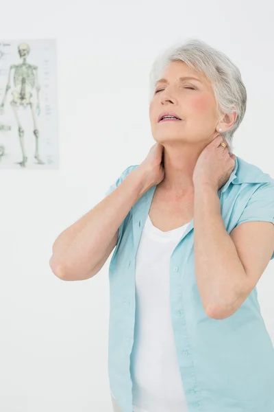 Seniorin leidet unter Nackenschmerzen in Arztpraxis — Stockfoto