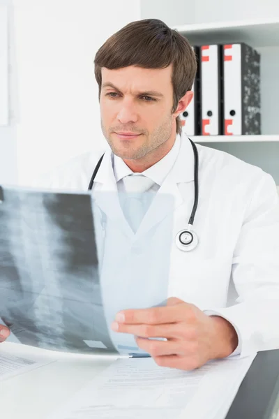 Médico masculino concentrado mirando la imagen de rayos X de la columna vertebral —  Fotos de Stock