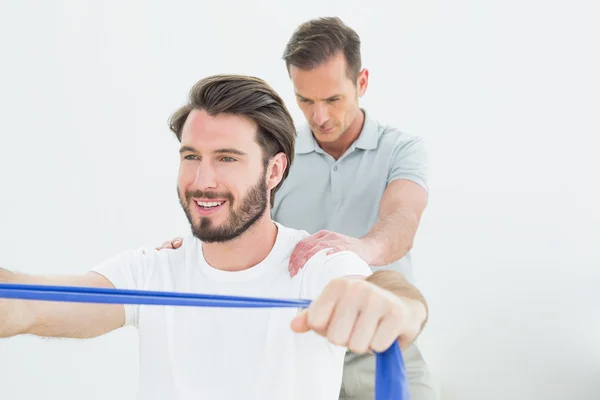 Mannelijke therapeut helpen een lachende man met oefeningen — Stockfoto