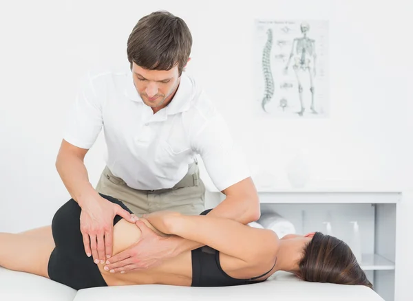 Fisioterapeuta masajeando espalda de mujer en consultorio médico — Foto de Stock